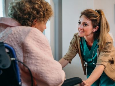 Female doctor talking to elderly female patient in a wheelchair