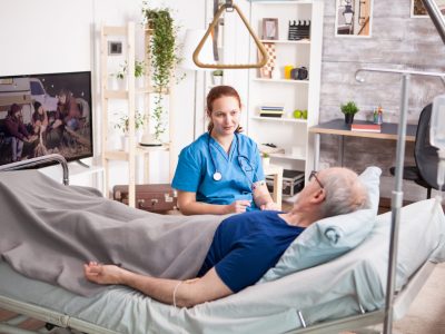 Female doctor with stethoscope sharing comfort to old man in nursing home.